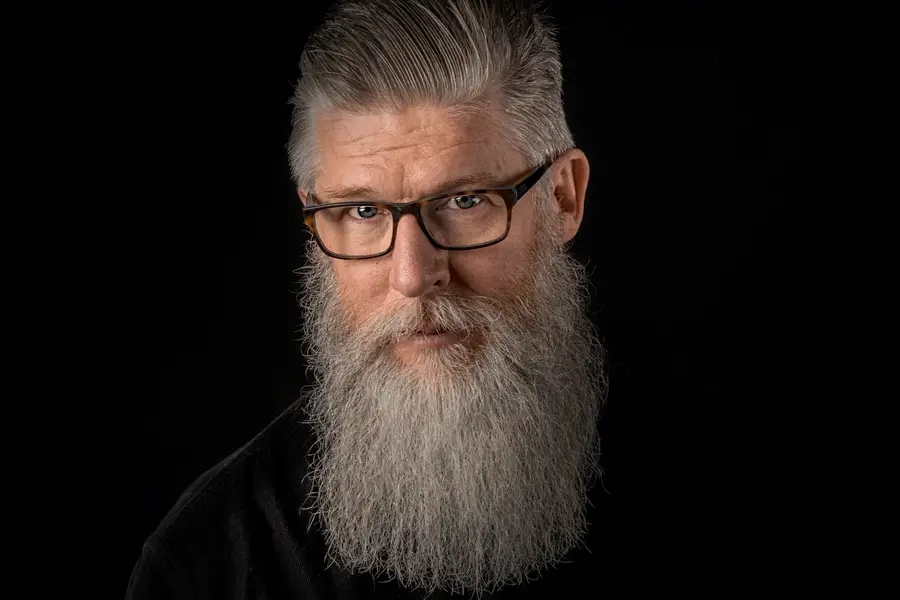 Barbe longue soigneusement peignée avec peigne en bois devant un miroir