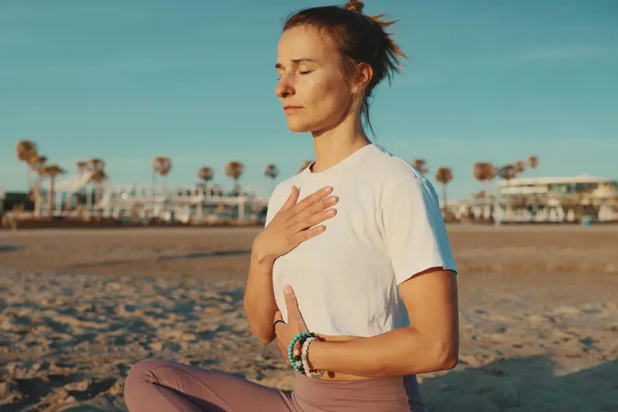 Personne assise près d’une fenêtre pratiquant une respiration calme au lever du jour