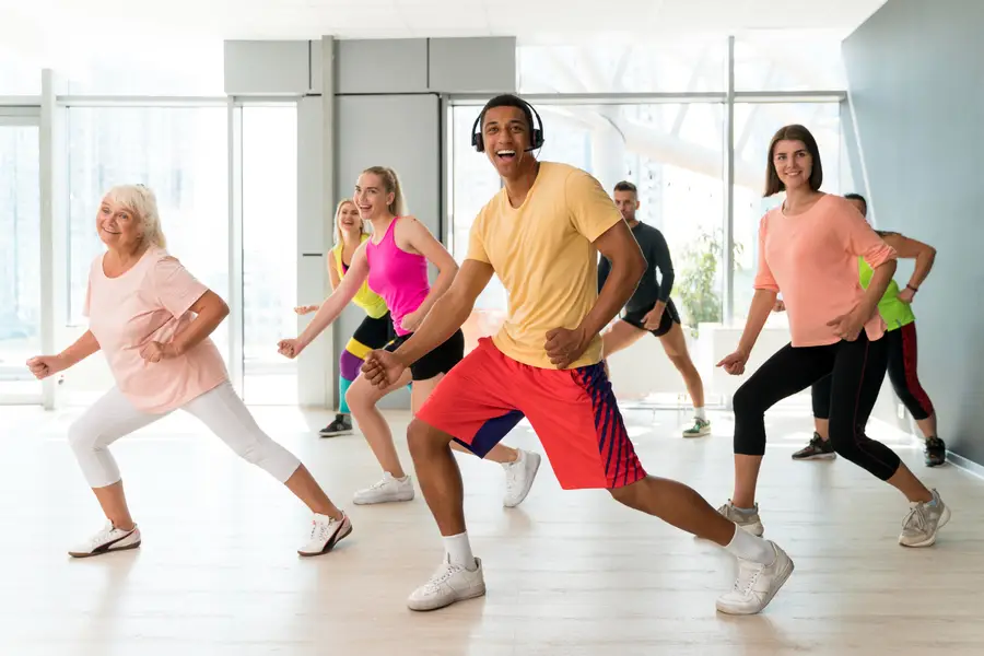Cours de zumba avec participants en appuis dynamiques et bras levés