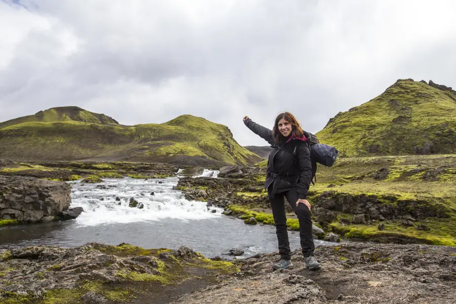 Voyageurs contemplant une cascade islandaise au milieu de falaises verdoyantes