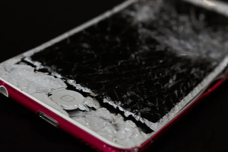 Smartphone posé sur une table avec écran fissuré et film protecteur transparent